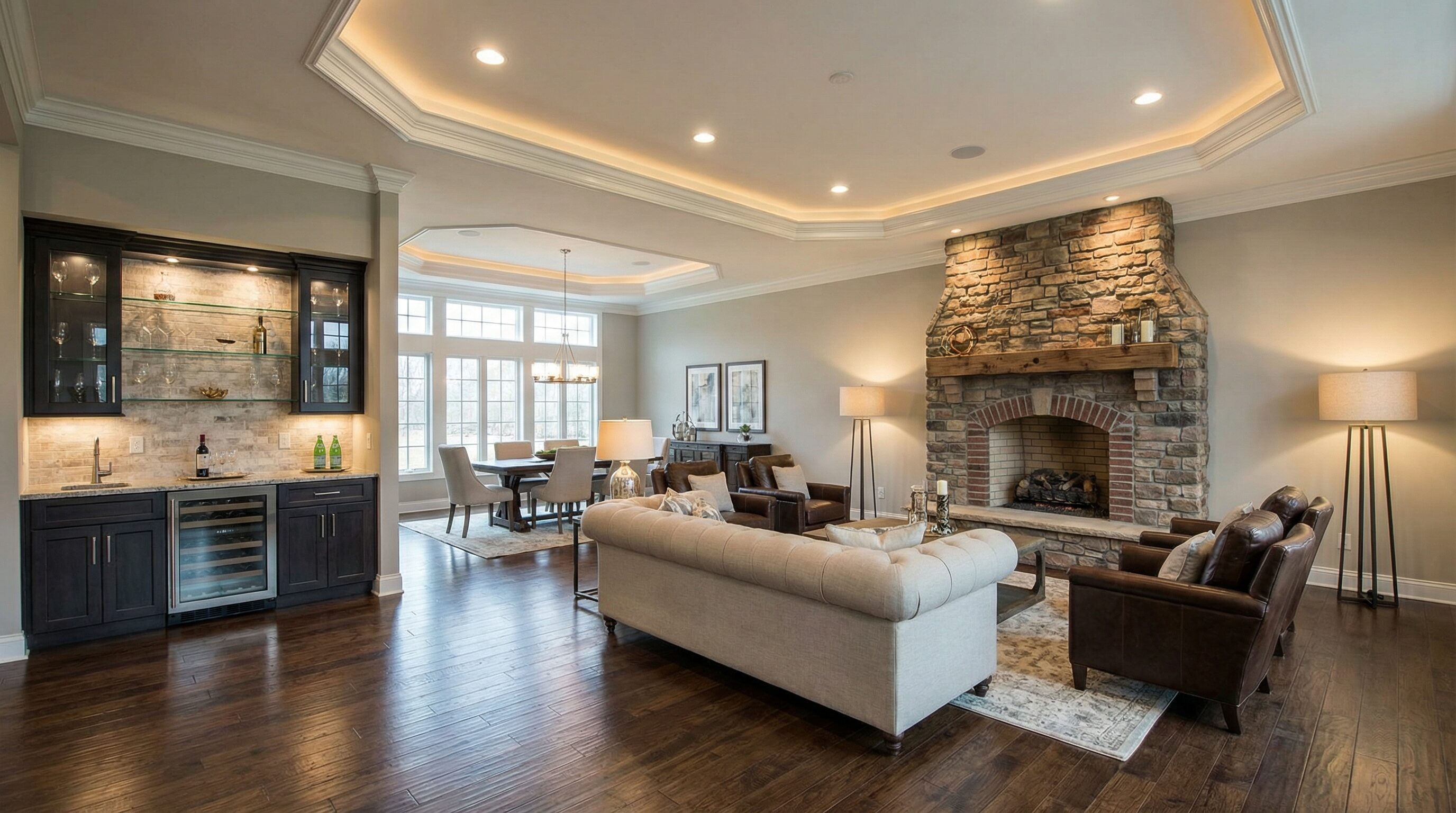 open concept first floor with tray ceiling, stone fireplace, wet bar and dark hardwood floors in Copley Ohio home